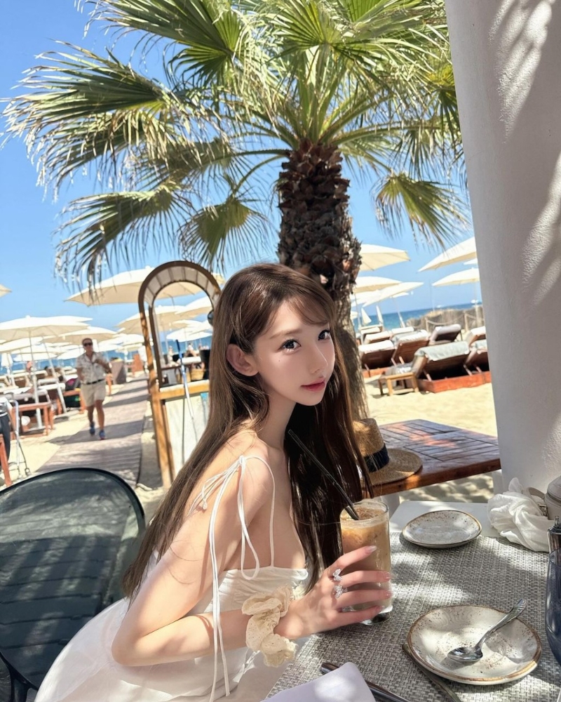 照片中可見Cammi換上多套服裝，分別是一套藍白條紋的比堅尼、白色吊帶連身裙、白色長袖防曬衣，在沙灘上擺出不同誘人姿勢。
