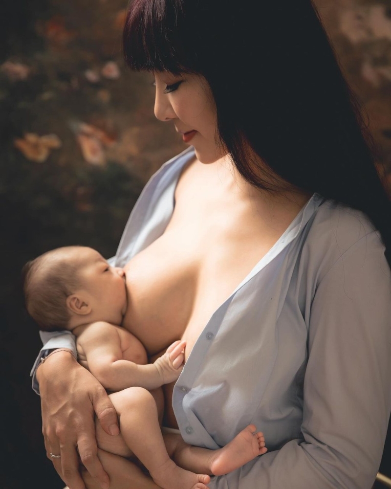 李宓穿上一件淺藍色襯衫，不過就將扣子解開露出35F傲人上圍，并將剛出生的雙胞胎女兒放在大腿上喂母乳及遮住重點部位。