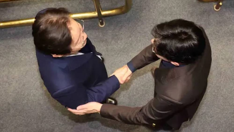南韓國會投票解除戒嚴后，韓國朝野兩大政黨黨魁在現場握手。 李在明（左）、韓東勛（右）。 中國新聞網截圖