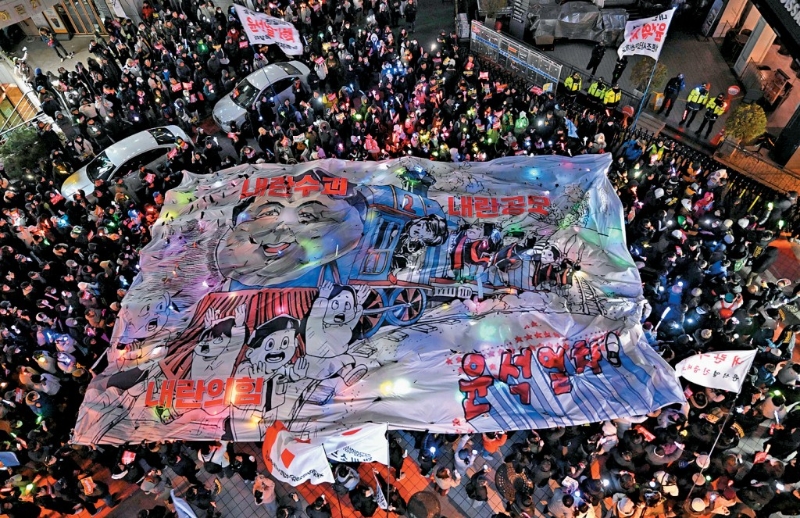 首爾示威者在執政國民力量黨總部外舉行「彈劾燭光集會」，展示諷刺總統尹錫悅的漫畫。