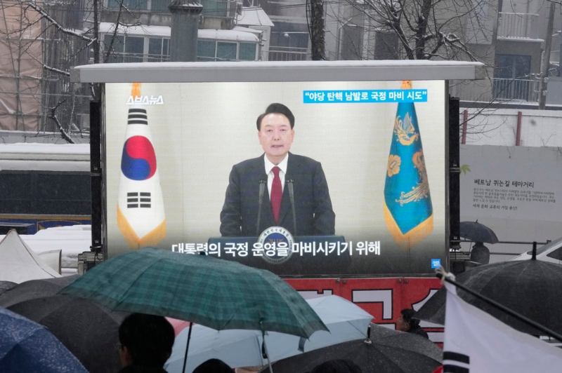 南韓總統尹錫悅因戒嚴遭國會彈劾停職，數度拒絕檢方傳喚調查?？偨y官邸外的挺引群眾5日圍在電視熒幕前收看新聞報導。（資料照／美聯社）