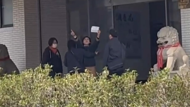 林岱樺與干員在南機站門口爆拉扯，一高舉標語激動喊“政治、司法干預初選”遭阻擋。