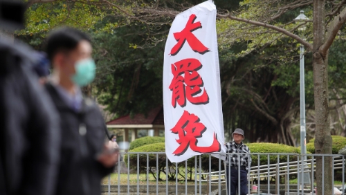 圖為民眾在民進黨中央黨部樓下高舉旗幟，要求黨主席賴清德對大罷免表態。